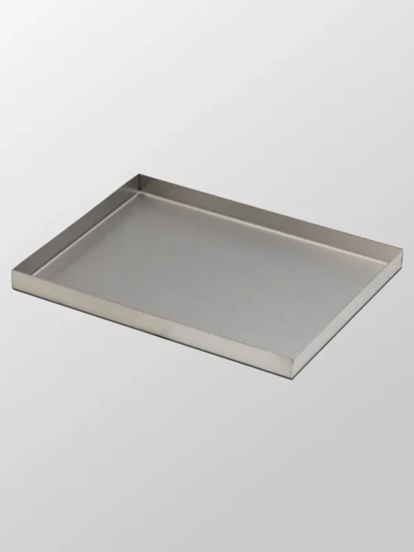 Dekorbricka Mellan är en rektangulär, grund bricka med upphöjda kanter i borstat rostfritt stål, avbildad mot en enfärgad ljusgrå bakgrund.