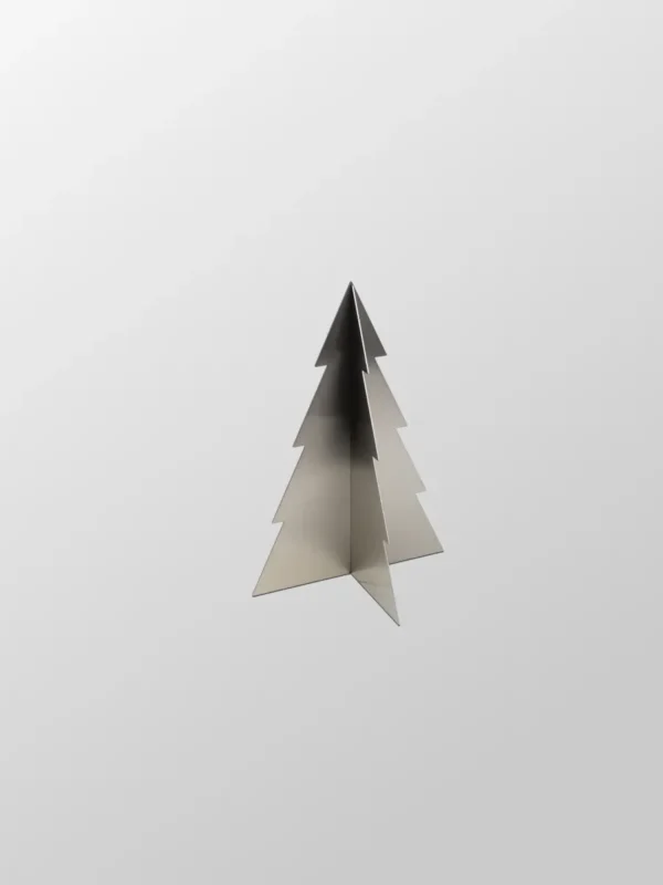 Julgran Liten är en minimalistisk julgransskulptur i borstat rostfritt stål med plana, korsande paneler mot en enfärgad ljusgrå bakgrund.