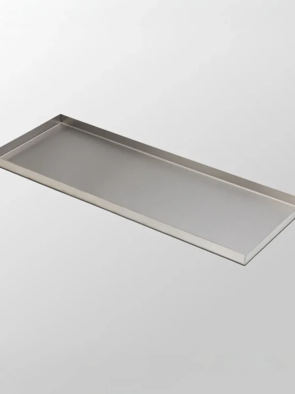 Dekorbricka Mellan är en rektangulär bricka tillverkad av borstat rostfritt stål med upphöjda kanter och elegant svensk design, som visas på en slät ljusgrå bakgrund.